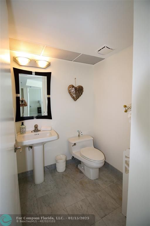 9341 Collins Avenue, Unit 1003 Surfside, FL 33154 - Photo 18 of 24 a bathroom with a toilet sink and mirror