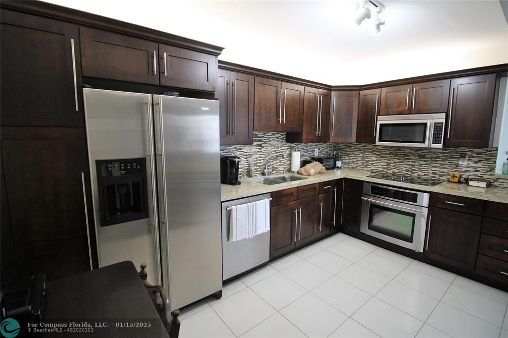 9341 Collins Avenue, Unit 1003 Surfside, FL 33154 - Photo 4 of 24 a kitchen with stainless steel appliances granite countertop a refrigerator a stove a sink and dishwasher