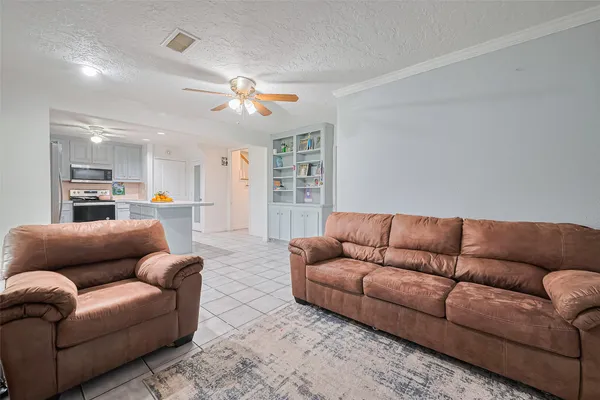 a living room with furniture kitchen view and a chandelier