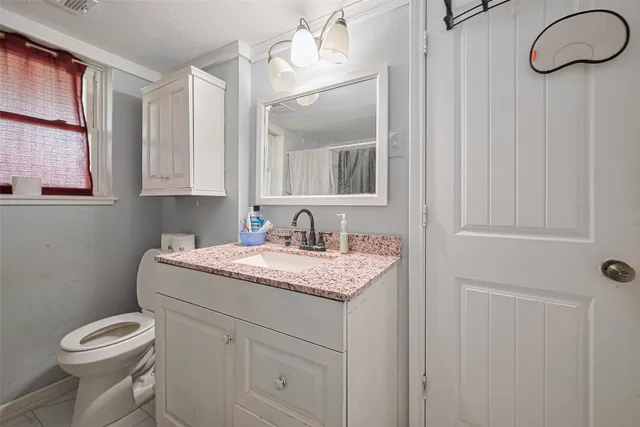a bathroom with a granite countertop sink and a toilet