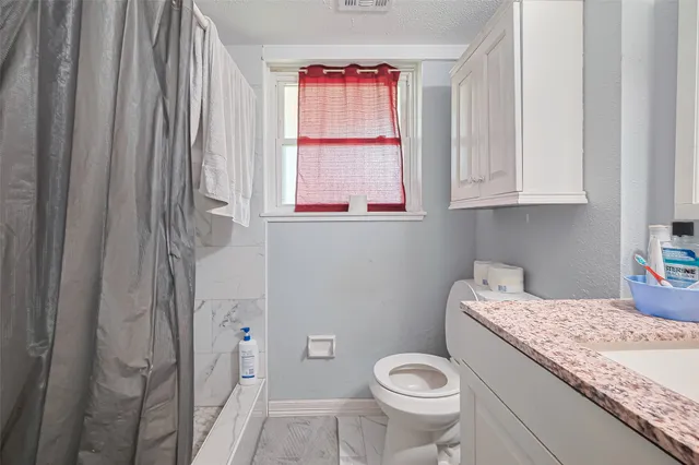 a bathroom with a granite countertop toilet sink and mirror