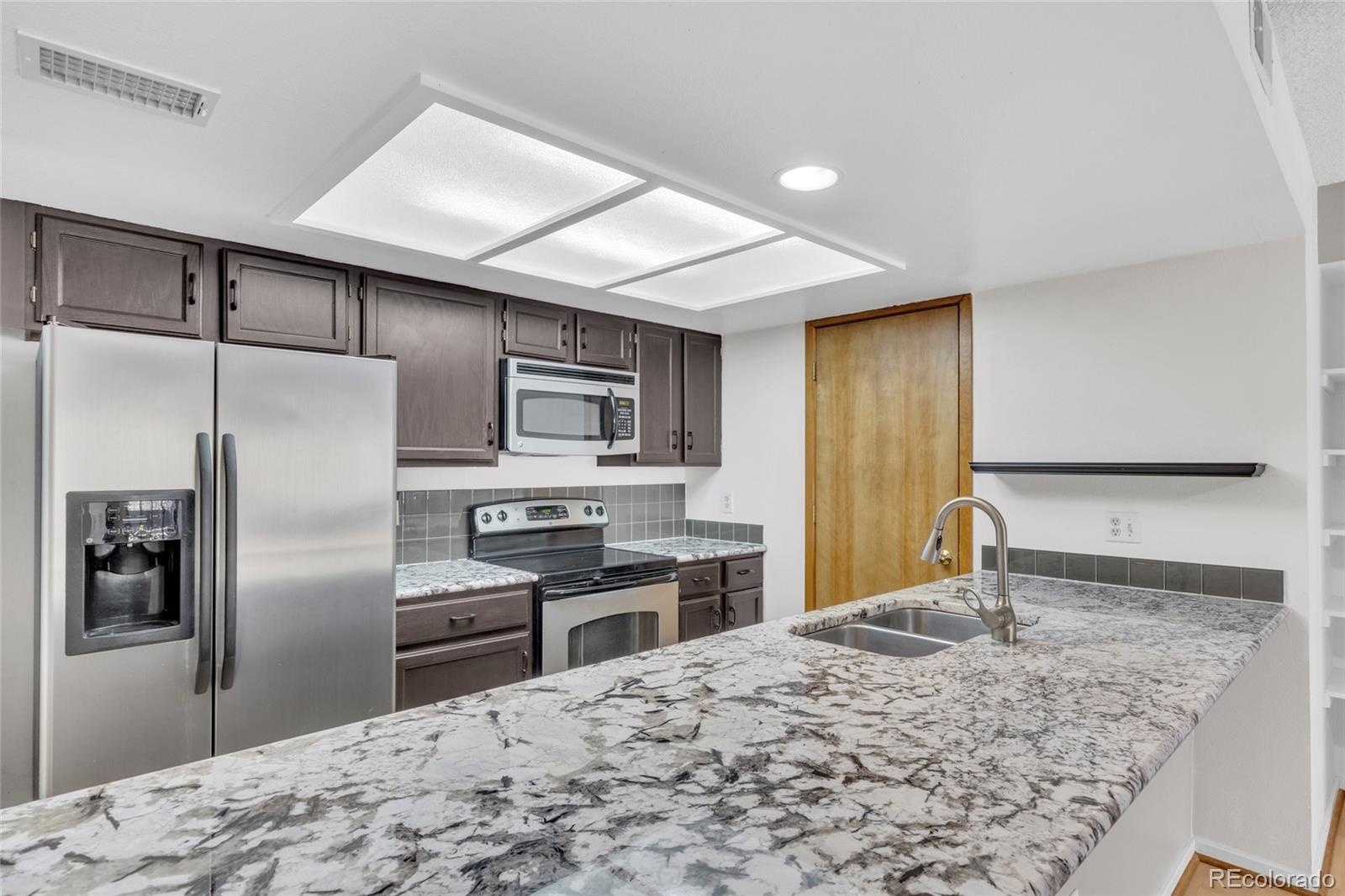 23537 Genesee Village Road Golden, CO 80401 - Photo 2 of 37 a kitchen with stainless steel appliances kitchen island granite countertop a refrigerator sink and stove