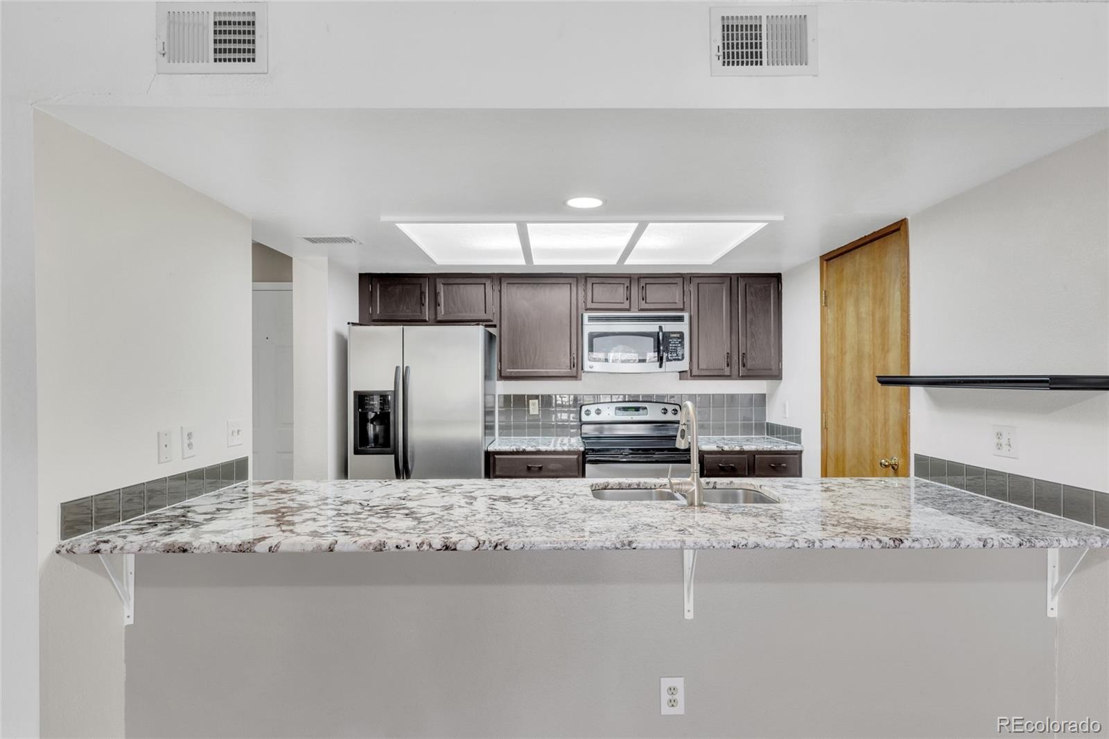 23537 Genesee Village Road Golden, CO 80401 - Photo 6 of 37 a kitchen with stainless steel appliances kitchen island granite countertop a refrigerator and cabinets