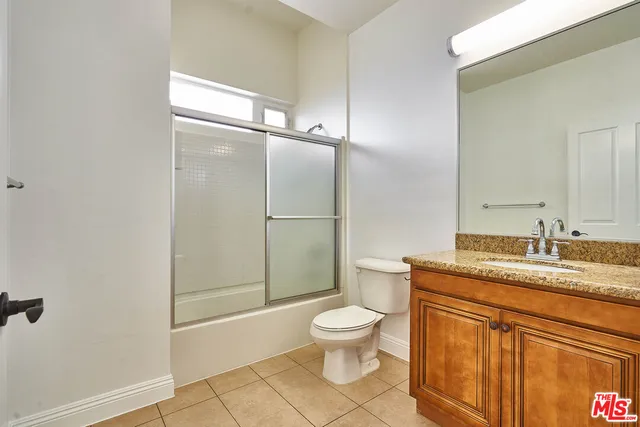 a bathroom with a granite countertop sink toilet mirror and shower