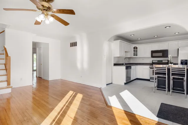 a kitchen with stainless steel appliances granite countertop a stove top oven a sink a dining table and chairs with wooden floor