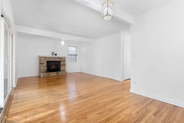 a view of empty room with wooden floor and fireplace