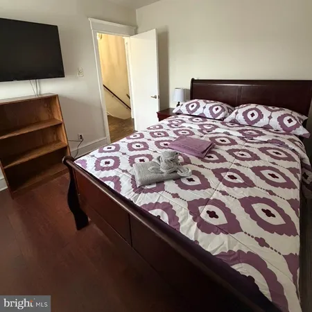 a bedroom with a bed and a flat tv screen on dresser