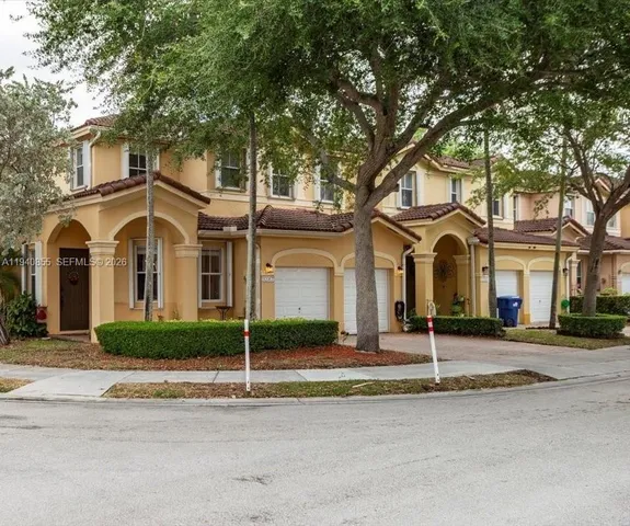 a view of a white house with large windows and a large tree