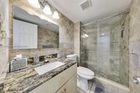 a bathroom with a granite countertop sink a toilet a mirror and bathtub