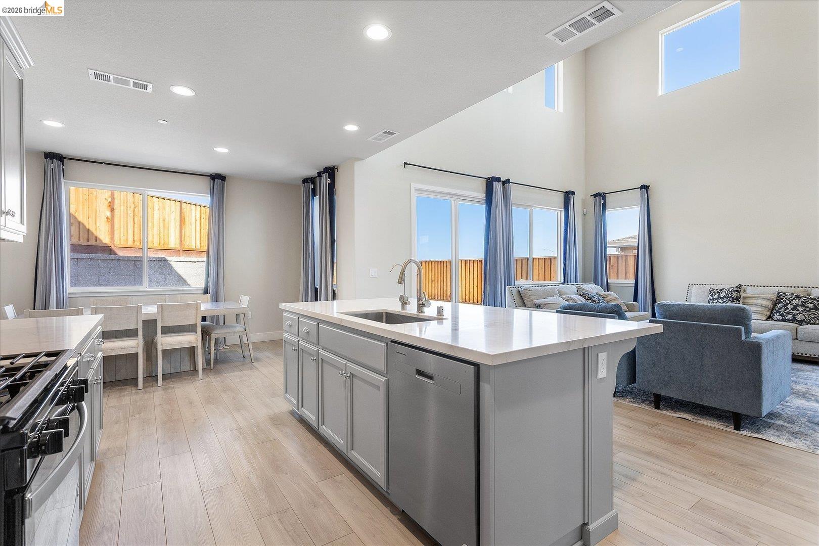 5601 Ridgepoint Way Antioch, CA 94531 - Photo 13 of 59 Open-concept living area with a kitchen island featuring a stainless steel sink, a gas range, and wood-finish flooring throughout