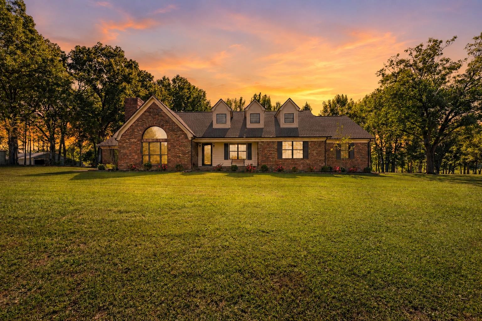 650 Blain Road Rossville, TN 38066 - Photo 32 of 32 Beautiful brick home showcased at sunset, highlighting its timeless architecture, inviting front porch, and picturesque setting on approximately 13 private acres.
