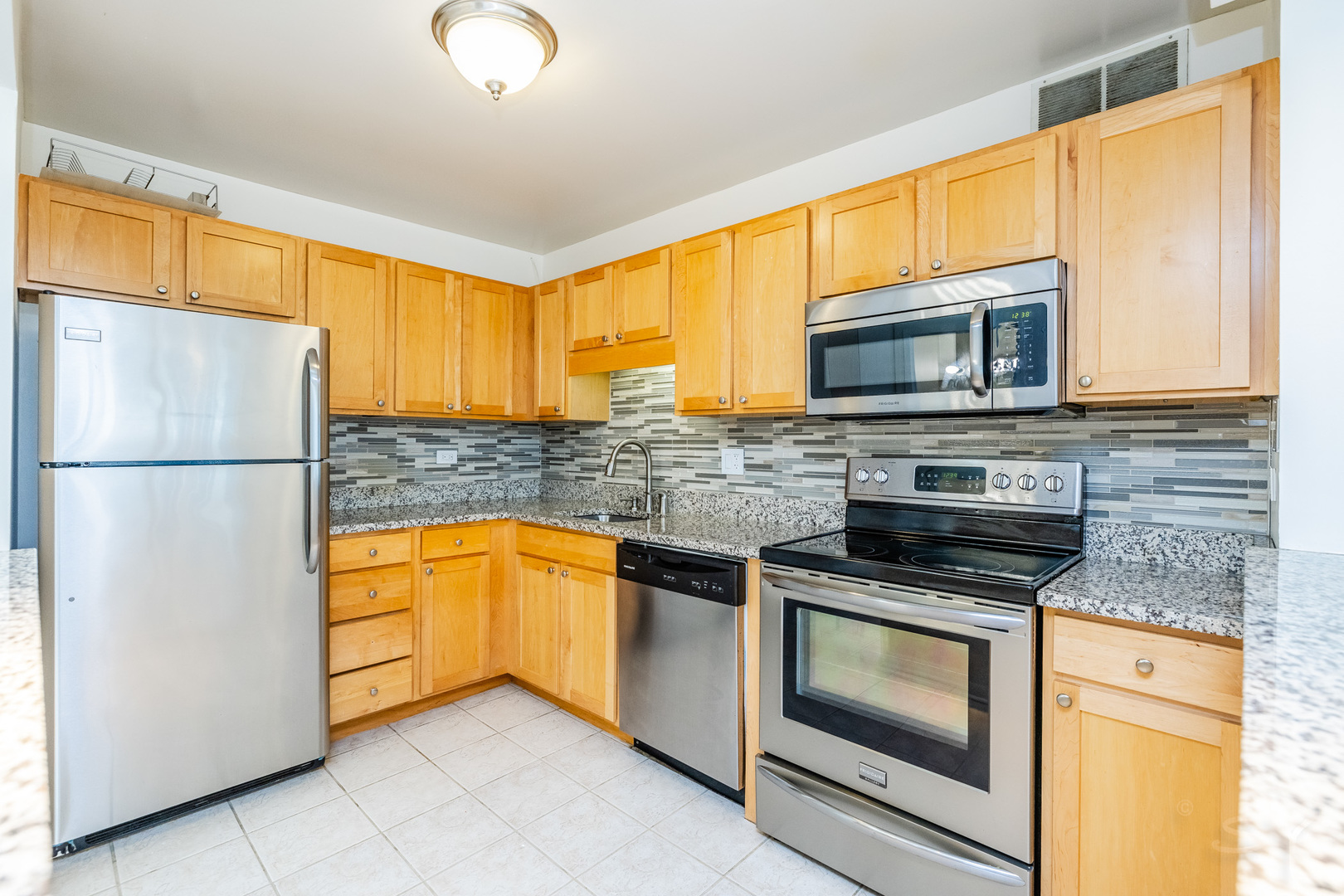 211 East Ohio Street, Unit 2606 Chicago, IL 60611 - Photo 12 of 32 a kitchen with stainless steel appliances granite countertop a stove top oven microwave and refrigerator