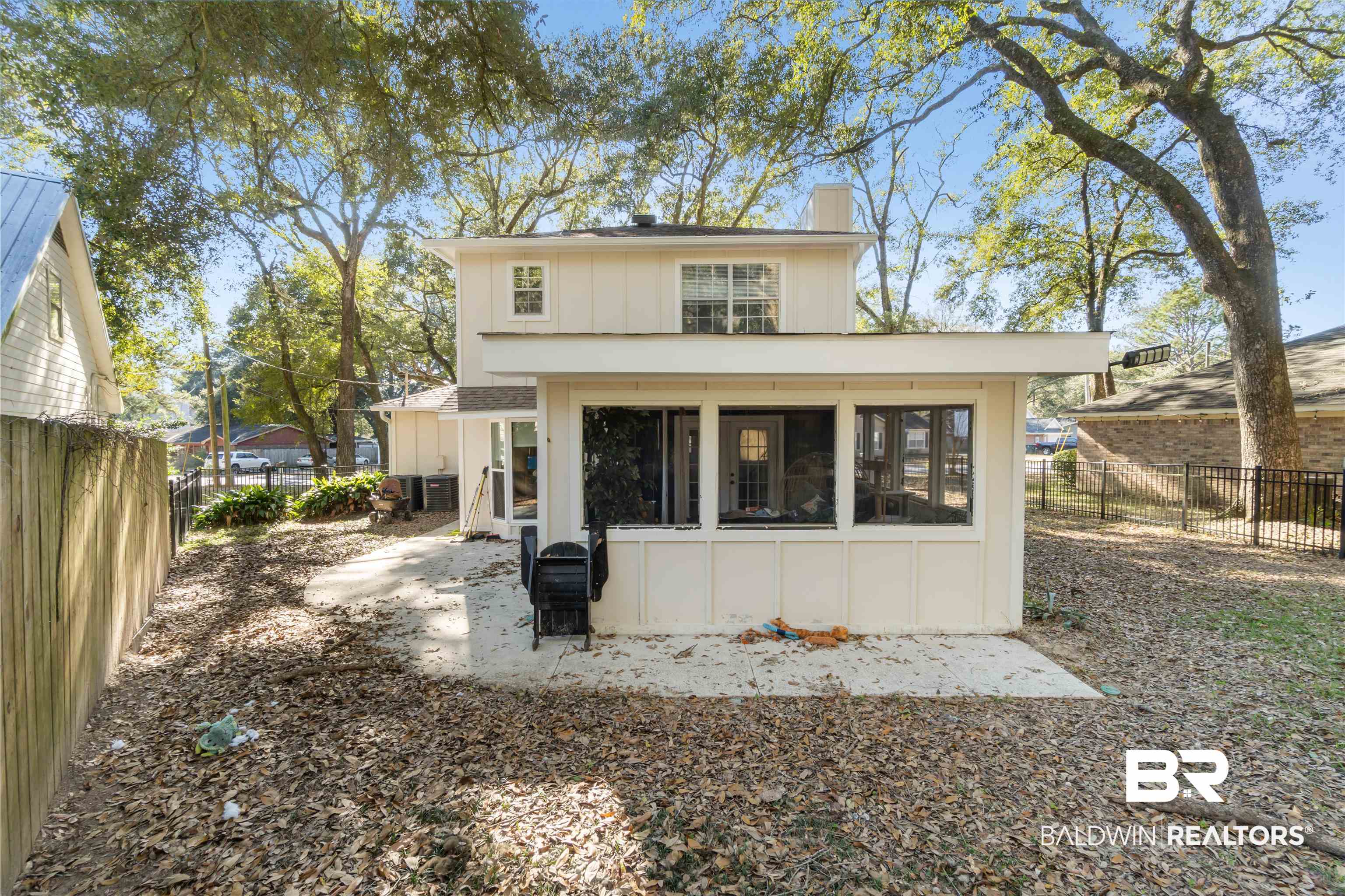 Rear view of house with a sunroom, a fenced backyard, a chimney, board and batten siding, and a patio