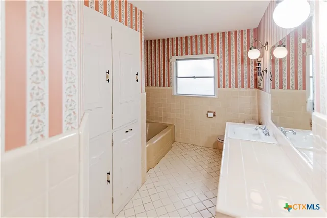 a spacious bathroom with a bathtub sink and mirror