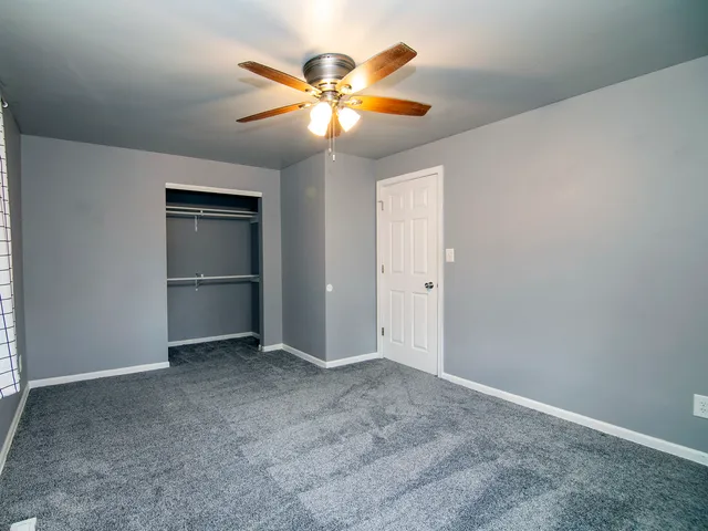 an empty room with closet and fan