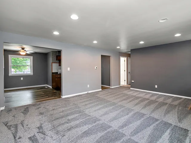 a view of an empty room with window and wooden floor