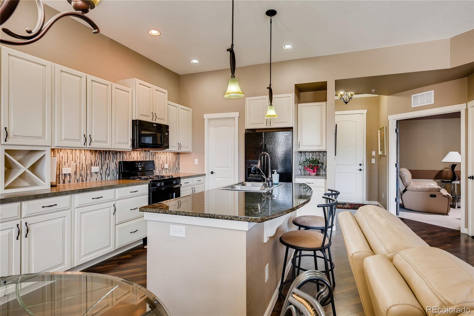 2366 Primo Road, Unit 205 Highlands Ranch, CO 80129 - Photo 8 of 28 a kitchen with kitchen island granite countertop a sink appliances cabinets and a counter top space