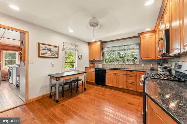 a kitchen with stainless steel appliances granite countertop a stove a sink and a microwave