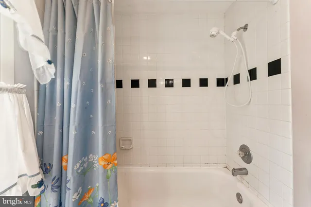 a living room with a black white checkered floor with a gaming machine and dining chairs