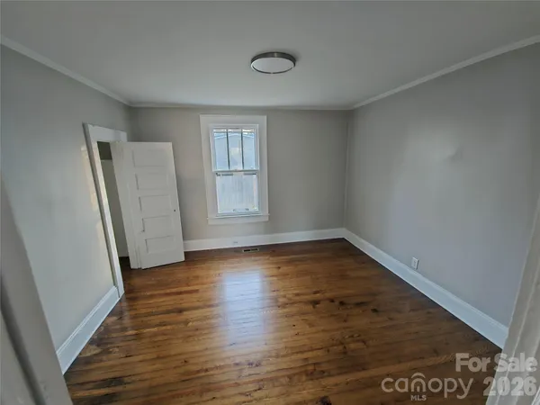 an empty room with wooden floor and window