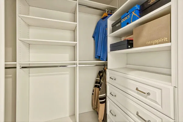 a view of walk in closet with clothes and shoes
