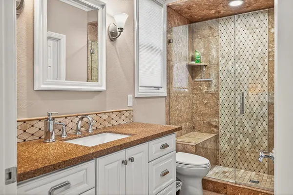 a bathroom with a granite countertop sink a toilet and a mirror