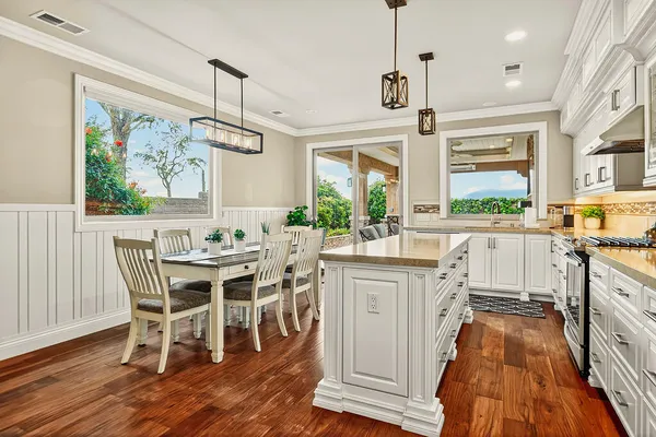 a kitchen with stainless steel appliances a dining table chairs and wooden floor