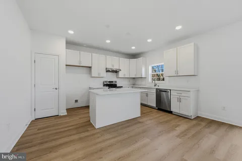 a kitchen with wooden floors white cabinets and stainless steel appliances