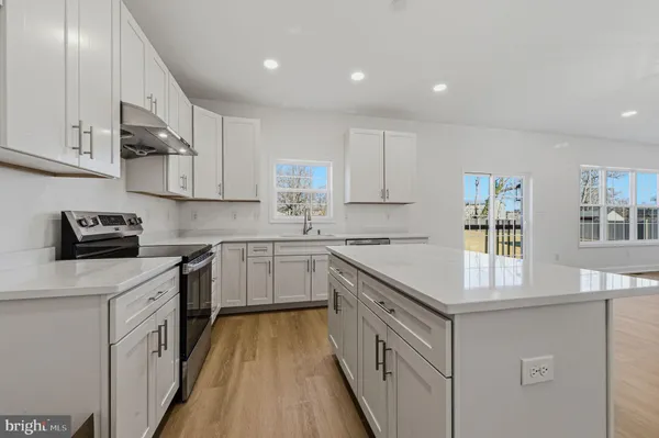 a kitchen with cabinets wooden floor and stainless steel appliances