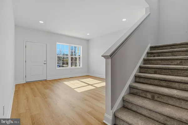a view of an empty room with stairs and wooden floor