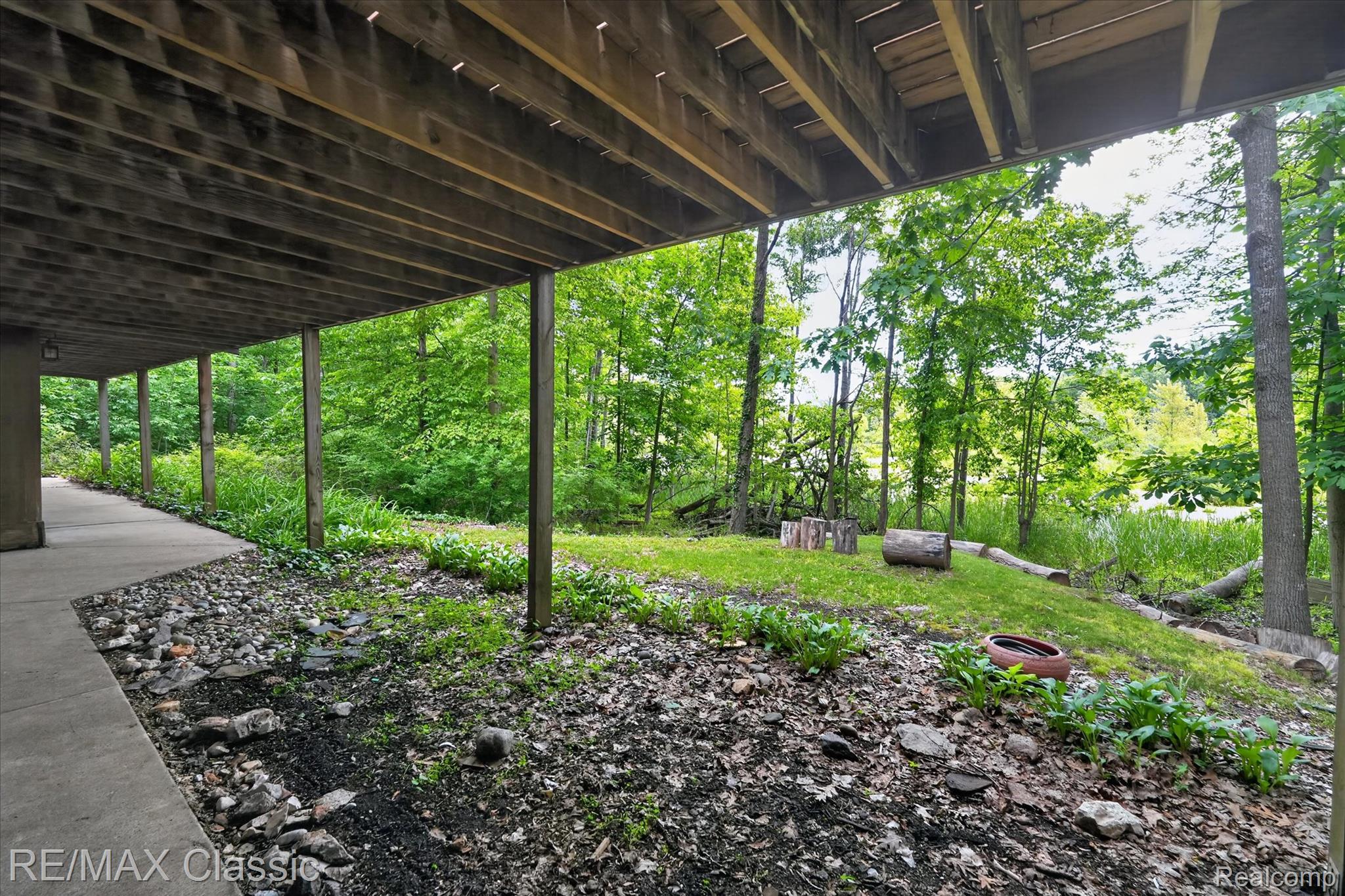12189 Gage Road Holly, MI 48442 - Photo 59 of 69 Under-deck patio with concrete pathway and natural landscaping