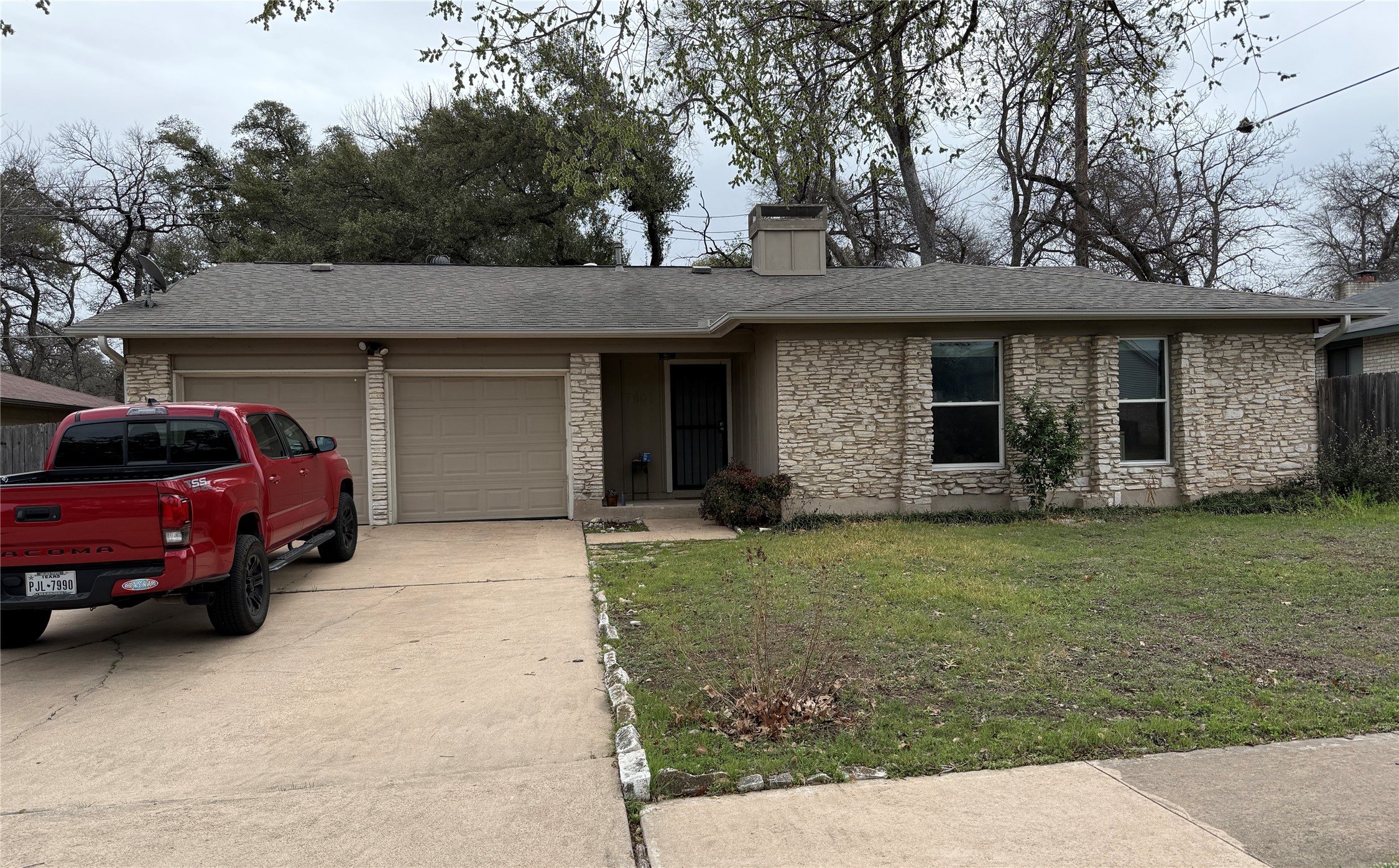 Ranch-style home with stone siding, a garage, concrete driveway, and a front yard