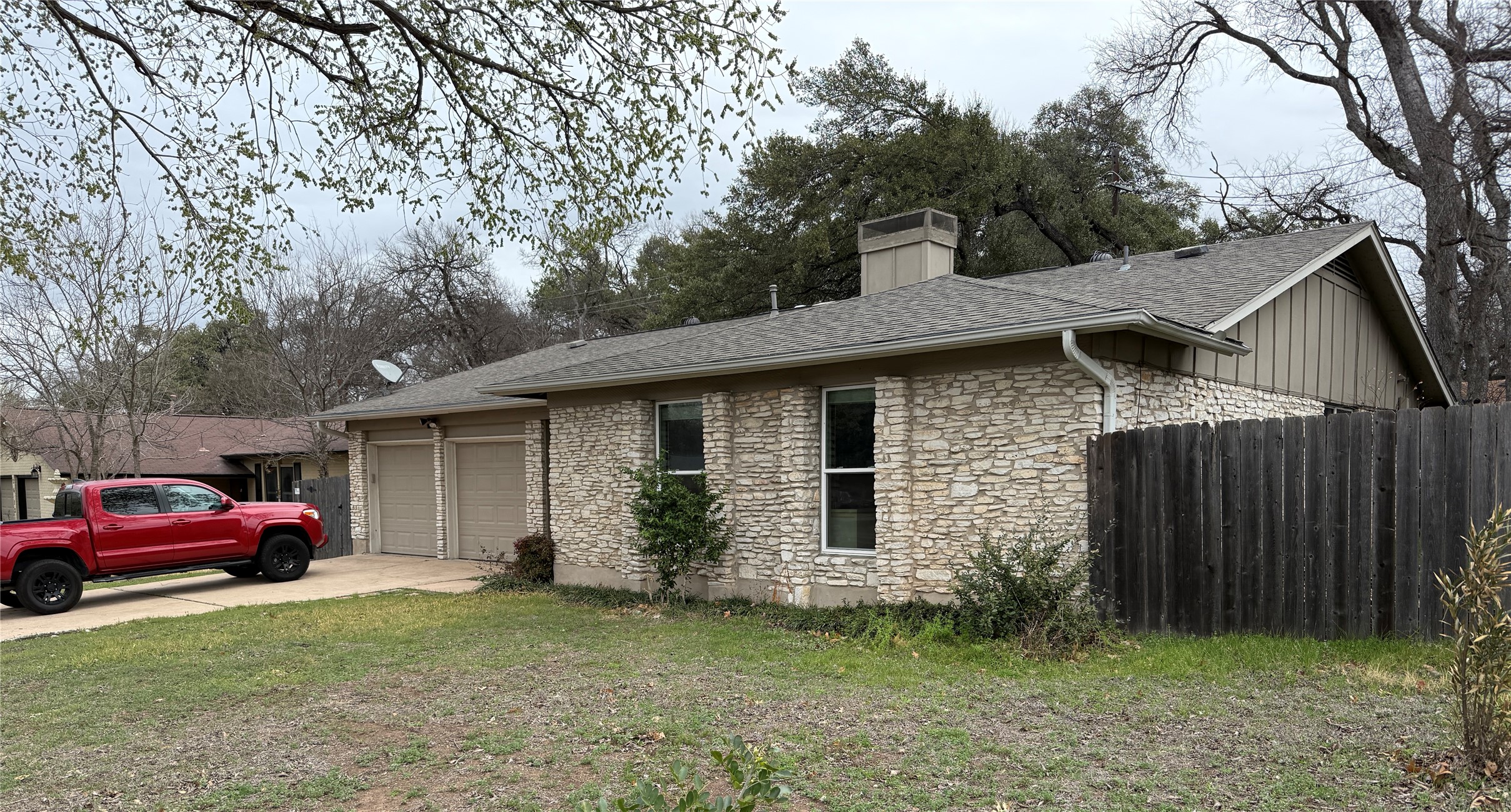 7501 West Gate Boulevard Austin, TX 78745 - Photo 2 of 33 View of side of property featuring stone siding, a chimney, driveway, a garage, and roof with shingles