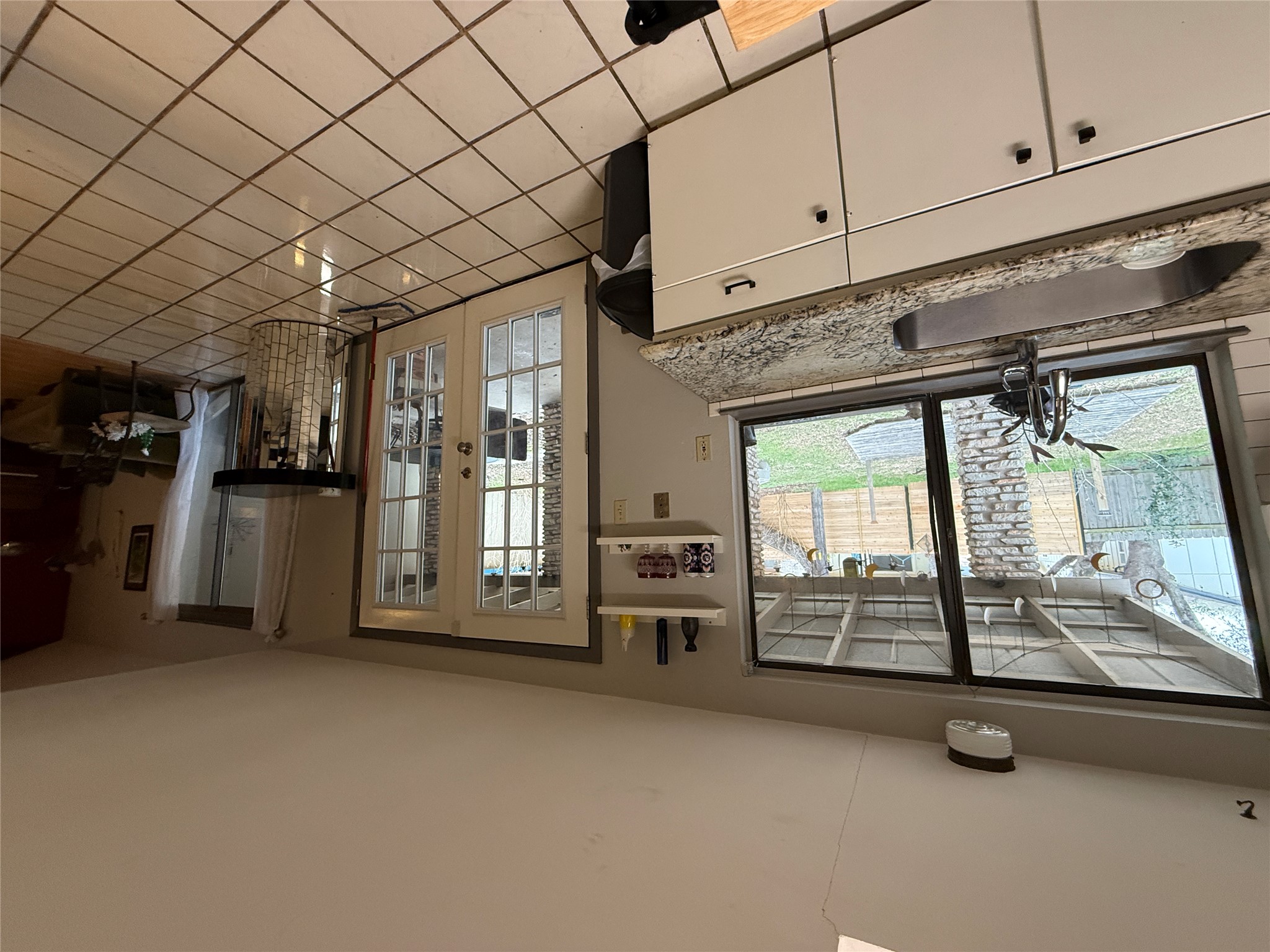 7501 West Gate Boulevard Austin, TX 78745 - Photo 8 of 33 Kitchen with french doors, light stone counters, white cabinetry, open shelves, and light tile patterned floors