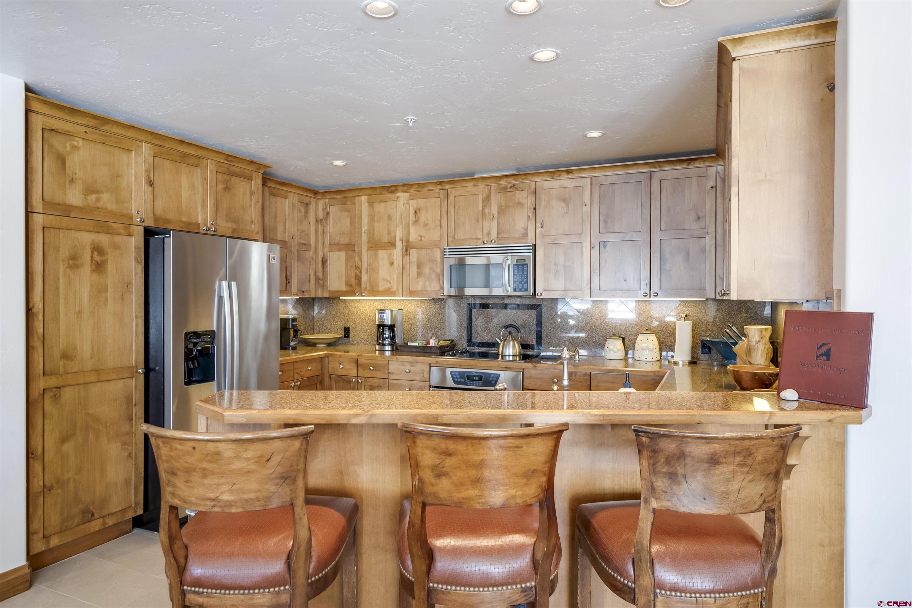 14 Hunter Hill Road, Unit C302 Crested Butte, CO 81225 - Photo 12 of 32 a kitchen with stainless steel appliances granite countertop a table chairs refrigerator and sink