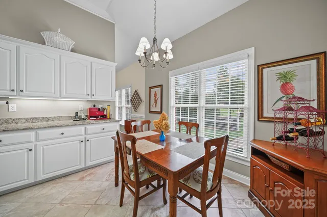 a dining room with wooden floor a chandelier a wooden table and chairs
