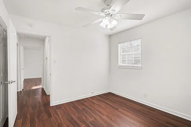 an empty room with wooden floor ceiling fan and windows