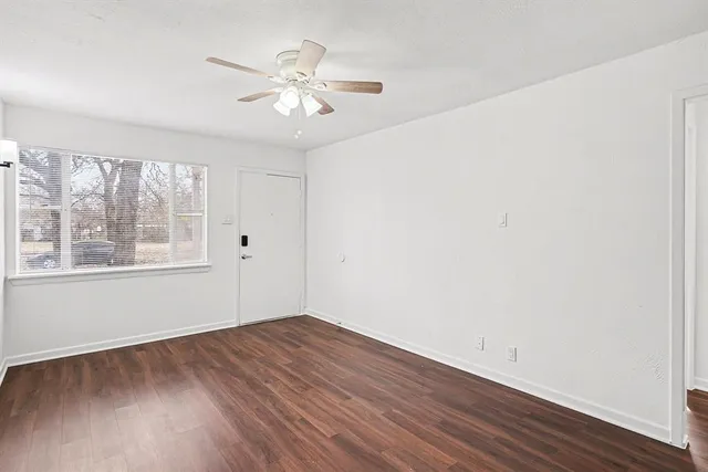 a view of an empty room with wooden floor and a window