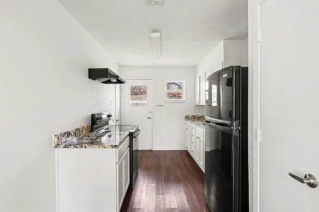 a kitchen with stainless steel appliances a refrigerator a sink a stove and white cabinets
