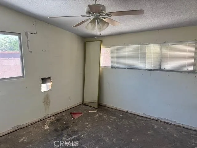 an empty room with windows and fan
