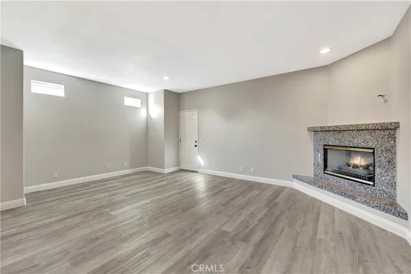 a view of an empty room with wooden floor fireplace and a window