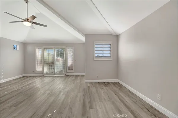 an empty room with wooden floor fan and windows