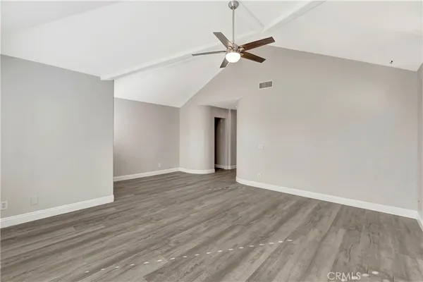 a view of an empty room with wooden floor and a ceiling fan
