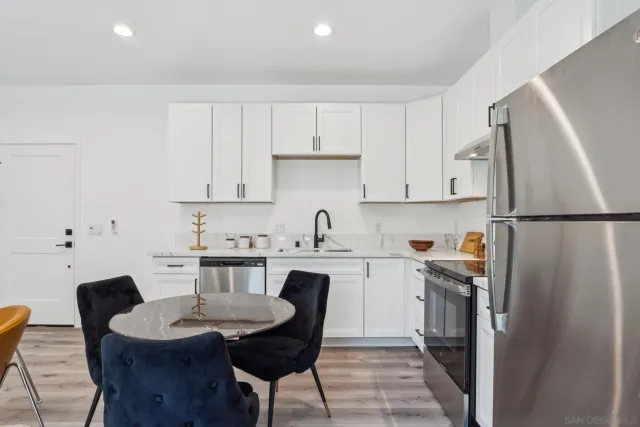 a kitchen with stainless steel appliances granite countertop a table chairs sink and cabinets