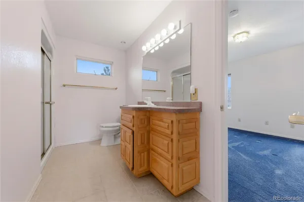 a bathroom with a granite countertop sink mirror vanity and toilet