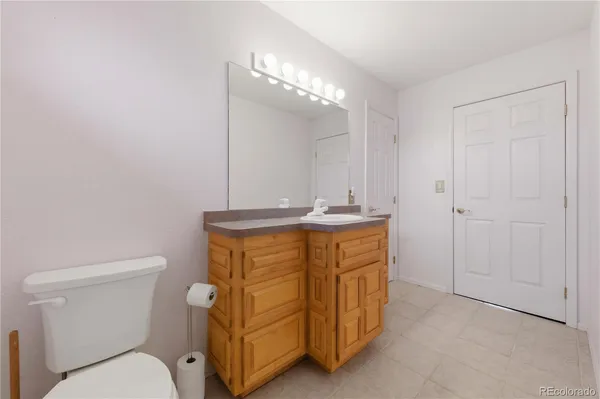 a bathroom with a granite countertop toilet sink and mirror
