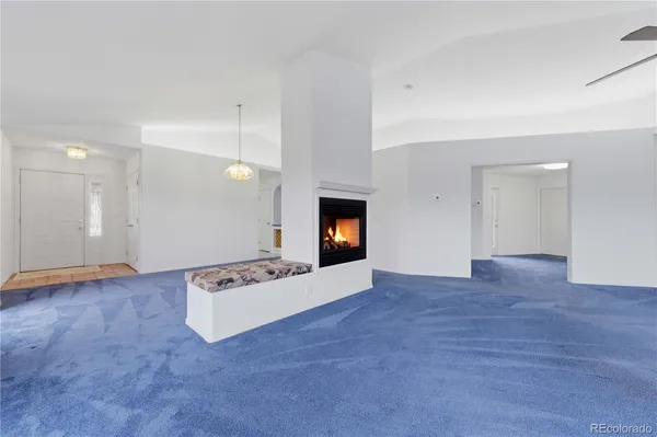 a view of an empty room with wooden floor and kitchen