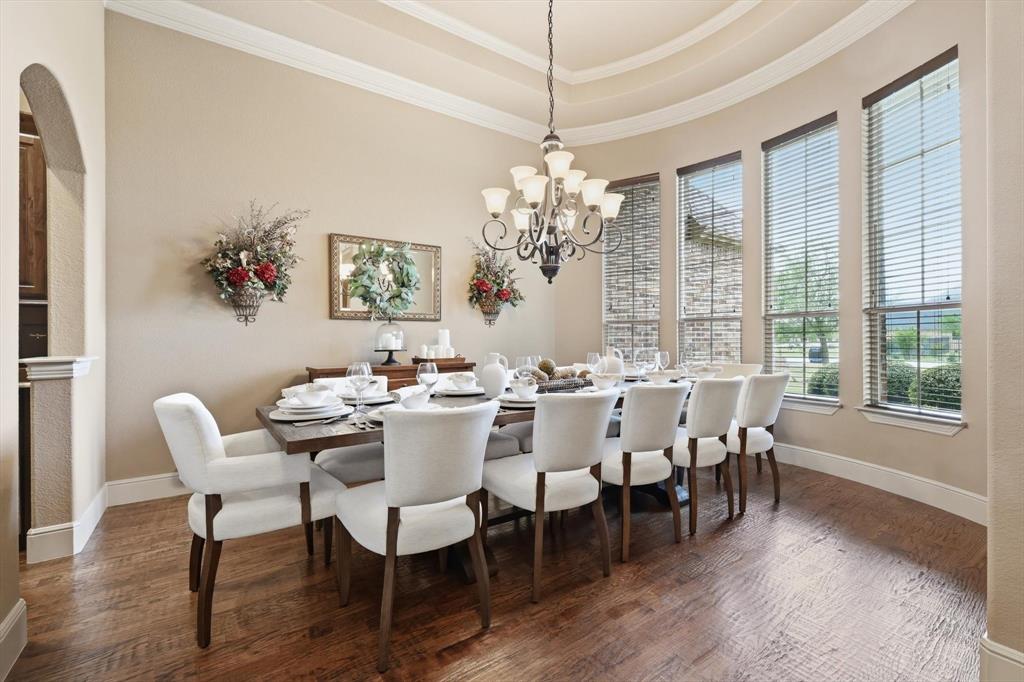 406 Spurgin Road Lucas, TX 75002 - Photo 3 of 39 Dining space with ornamental molding, dark wood finished floors, a chandelier, a raised ceiling, and arched walkways