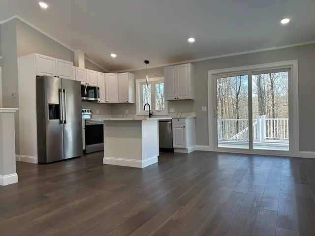 a kitchen with stainless steel appliances wooden floor and a refrigerator