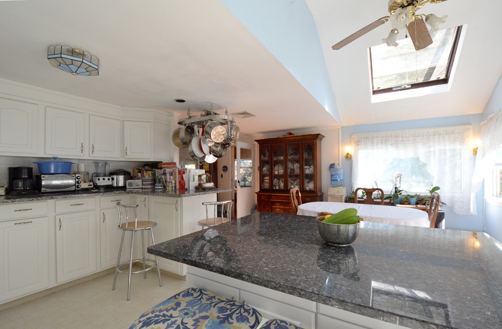 96 Doty Street Waltham, MA 02452 - Photo 3 of 15 a kitchen with stainless steel appliances granite countertop a sink a stove white cabinets with a dining table and chairs